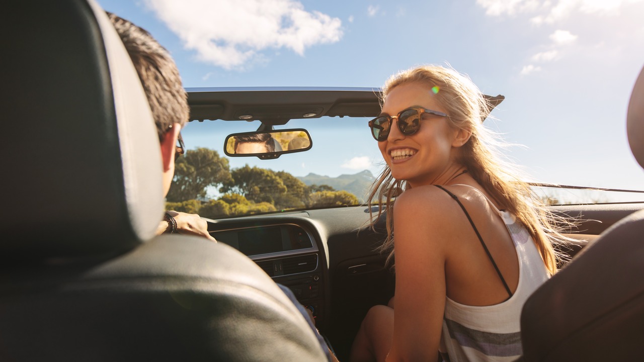 A young couple, happy in a car on a roadtrip.