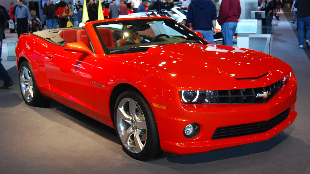 A red Chevrolet Camaro SS convertible at a car show, front 3/4 view