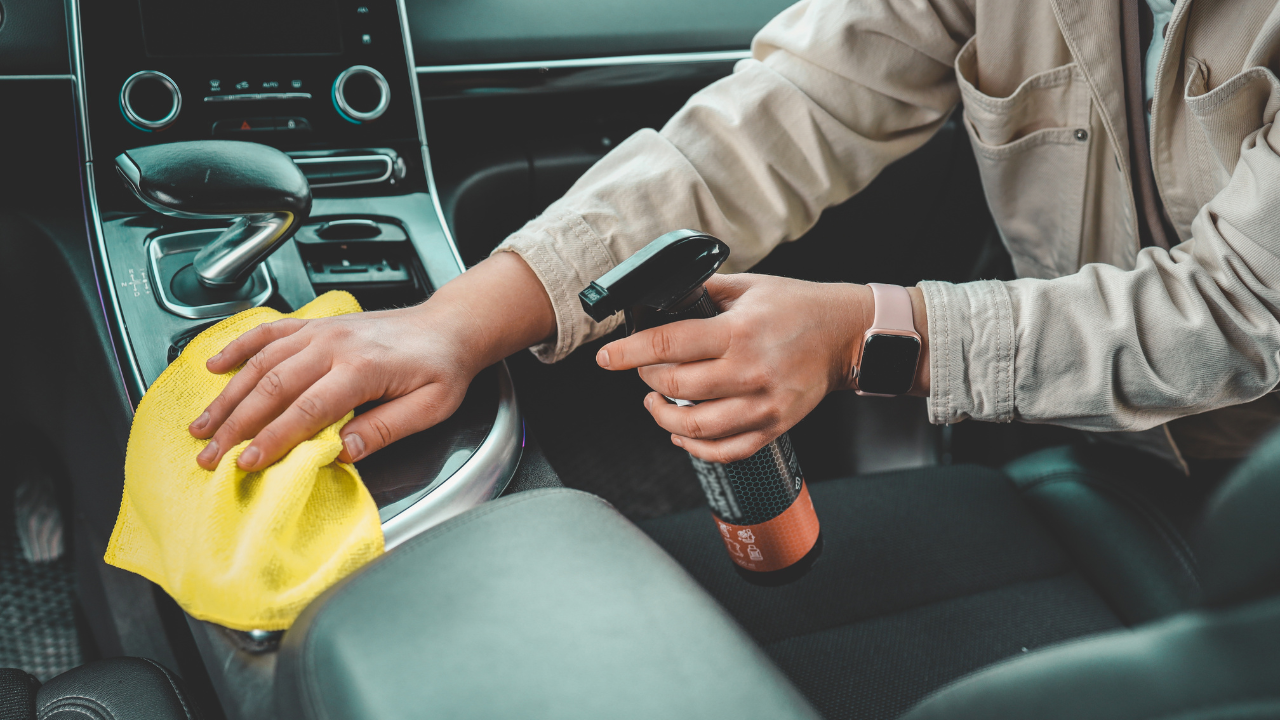 A woman at a car wash does a full dry-cleaning of all parts of a car using special chemistry, cloths, sponges and brushes. Concept of: Full car cleaning, Dry cleaning, Professional service. Car, Work.