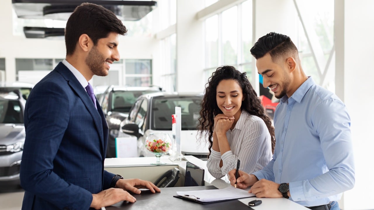 A couple at a rental car counter, signing paperwork.