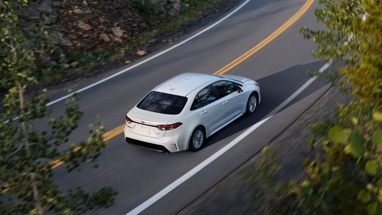 A White 2025 Toyota Corolla LE on a road in the sun outdoors.
