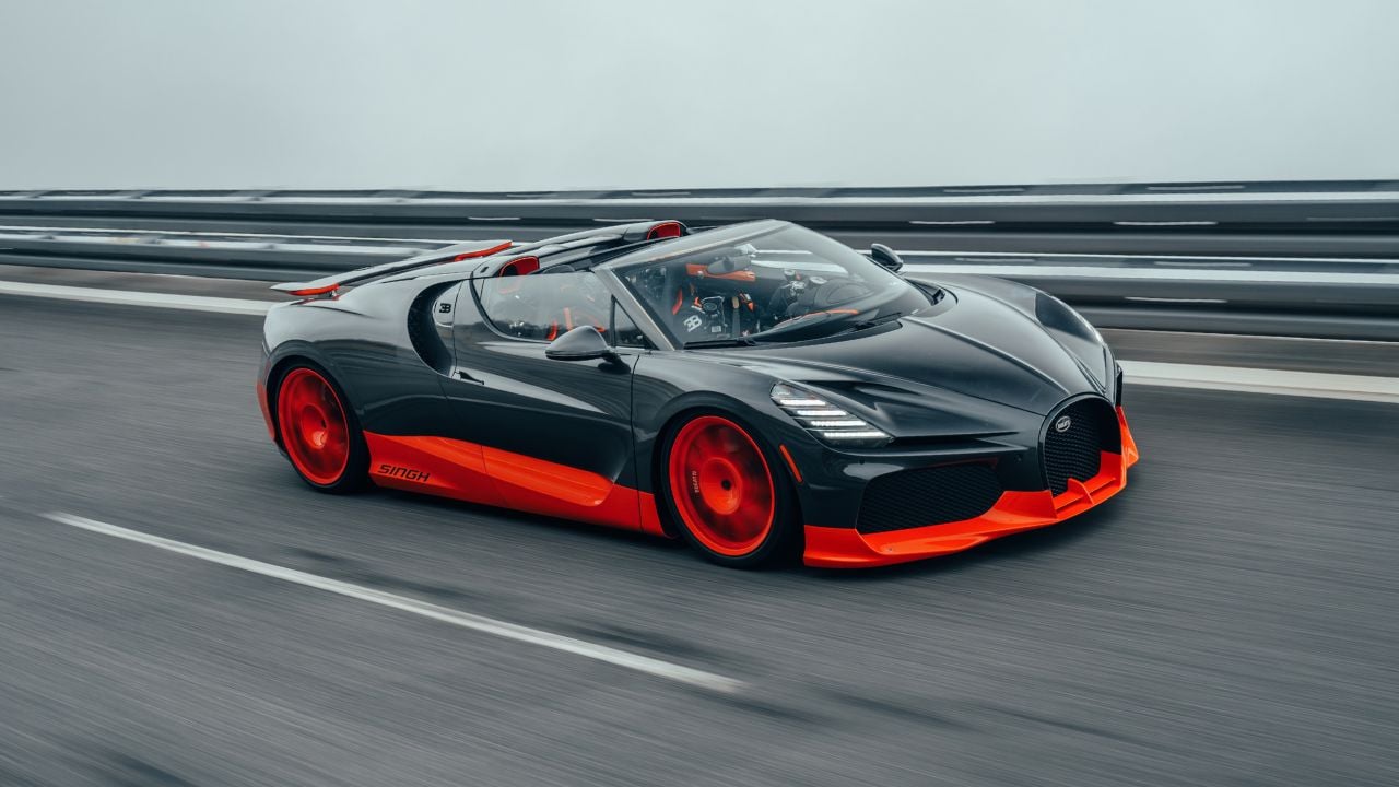 Black Bugatti W16 Mistral With Orange Accents Driving With Roof Down Front 3/4 View
