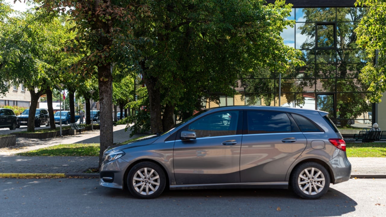 A minivan car parked under a tree for shade and heat protection