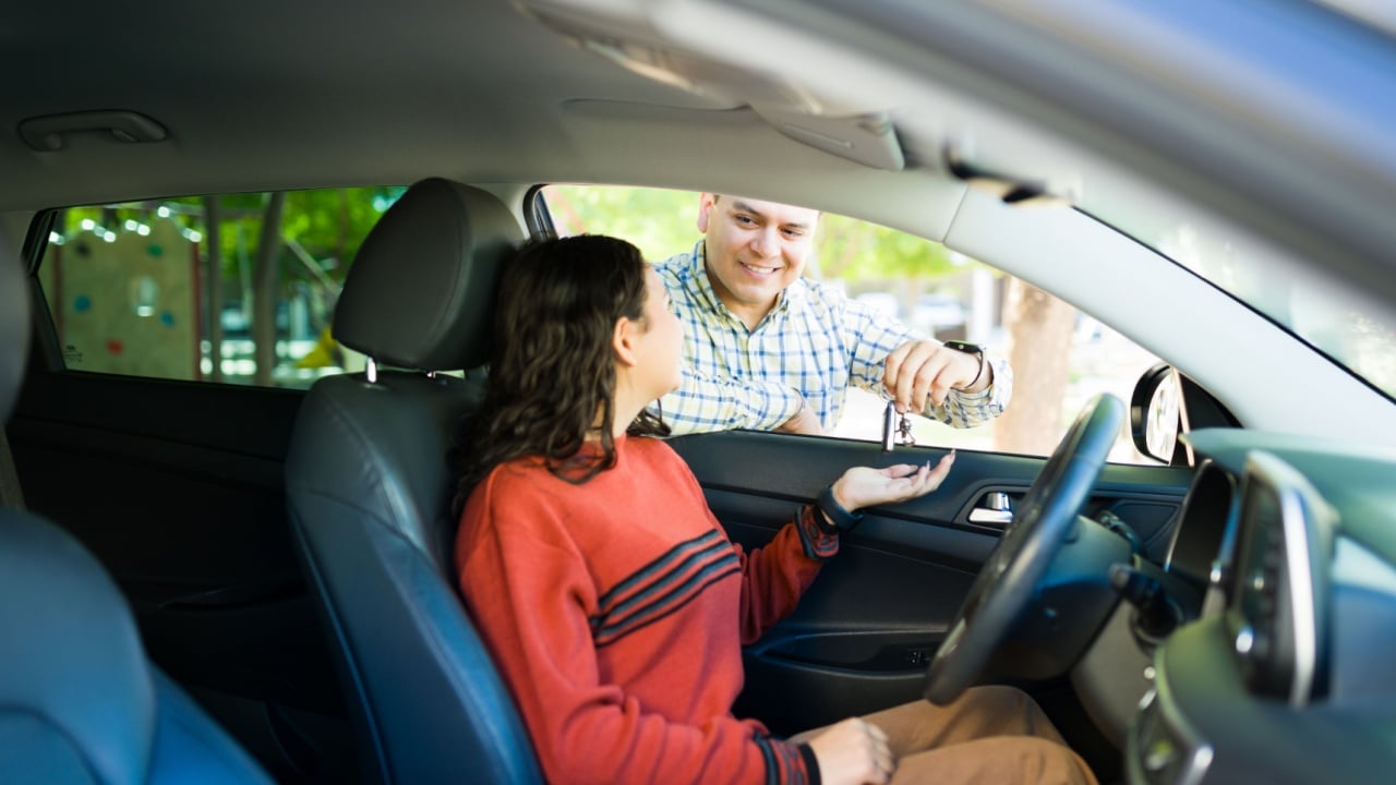 Proud dad entrusting car keys to his teenage daughter, marking a new phase of independence, trust, and responsibility as she embarks on learning to drive