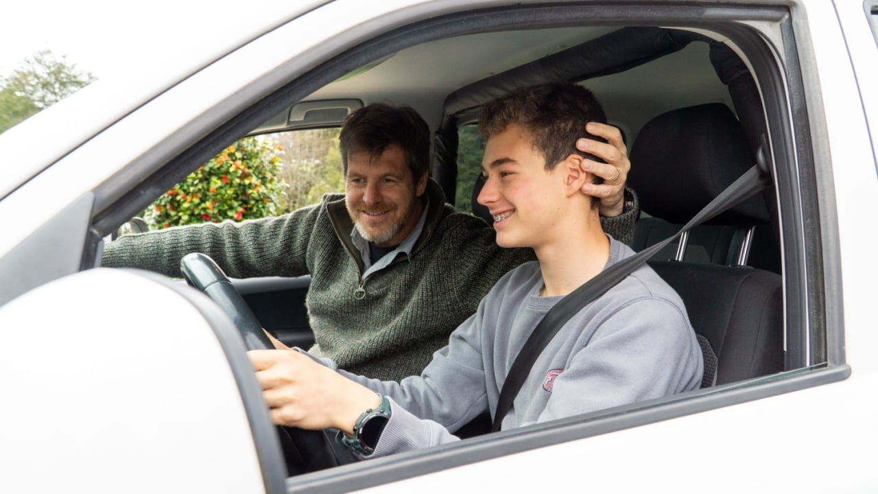 Proud father watching his teenage son drive.