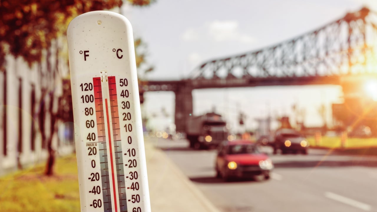 Thermometer in front of cars and traffic during heatwave