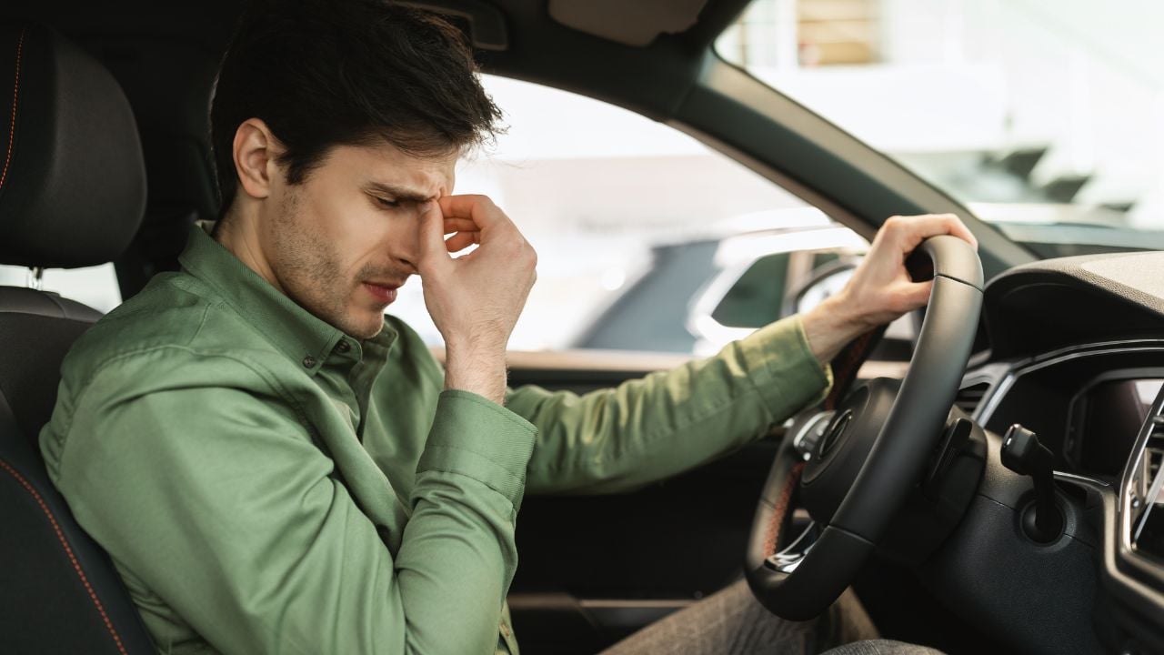 Unhappy young male client sitting on driver's seat of new car, disappointed with test drive, having doubts about buying automobile at modern dealership, copy space. Vehicle local distribution
