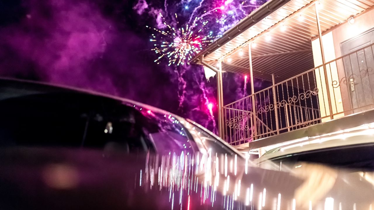 Fireworks illuminate the night sky above a balcony during celebrations. Bright fireworks burst in vibrant colors over a balcony at night.
