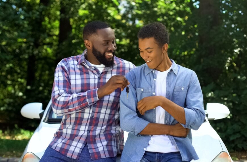 Happy dad giving car key to son, permission to drive, parenthood trust, family