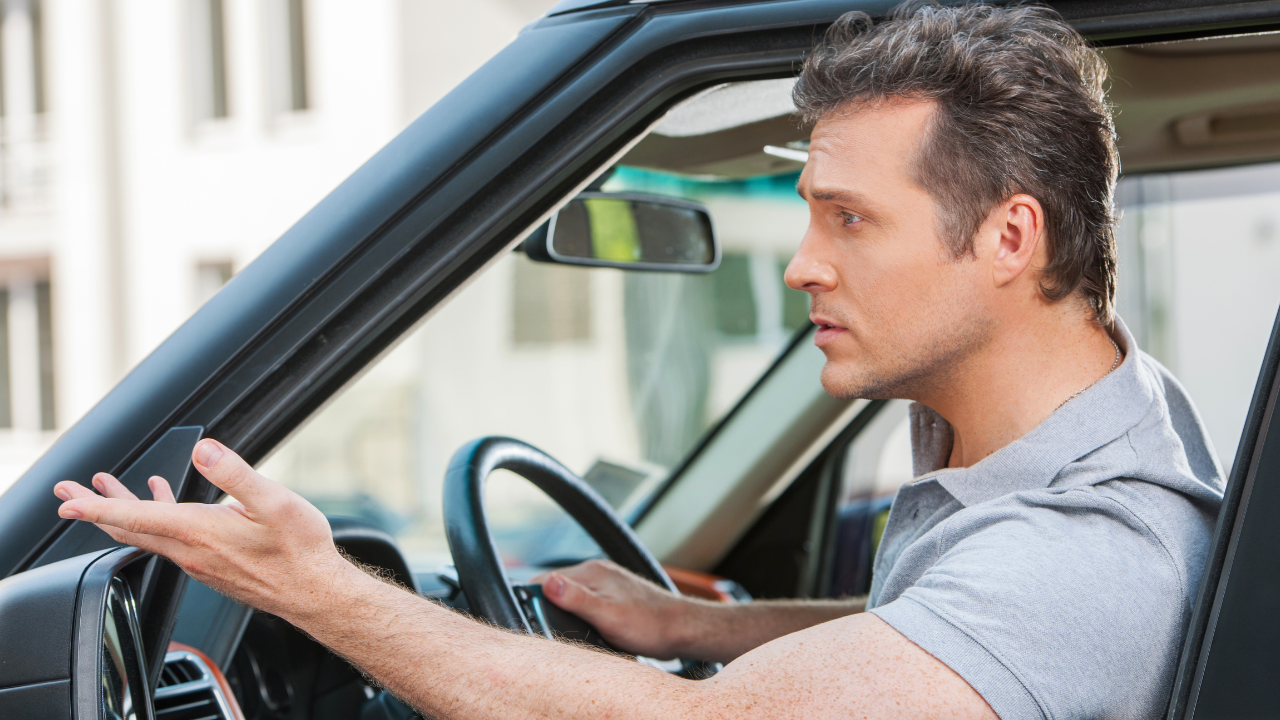 A man hand signaling from a car.