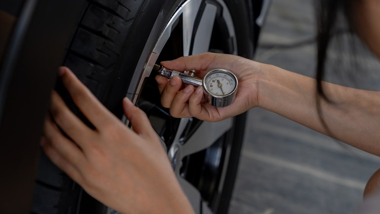 A picture of a woman checking tire pressure.