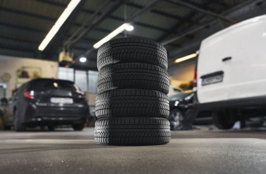 tire at repairing service garage background. Technician man replacing tyre in auto repair shop. Transportation and automotive maintenance concept