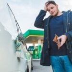 man with sad view and empty wallet at gas station. dollars money in car tank concept