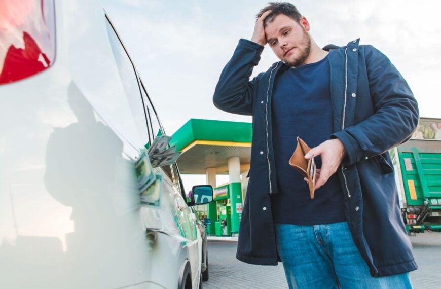 man with sad view and empty wallet at gas station. dollars money in car tank concept