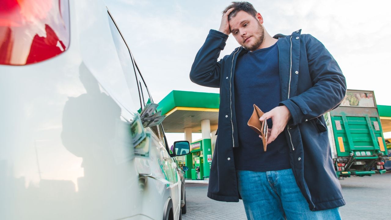 man with sad view and empty wallet at gas station. dollars money in car tank concept