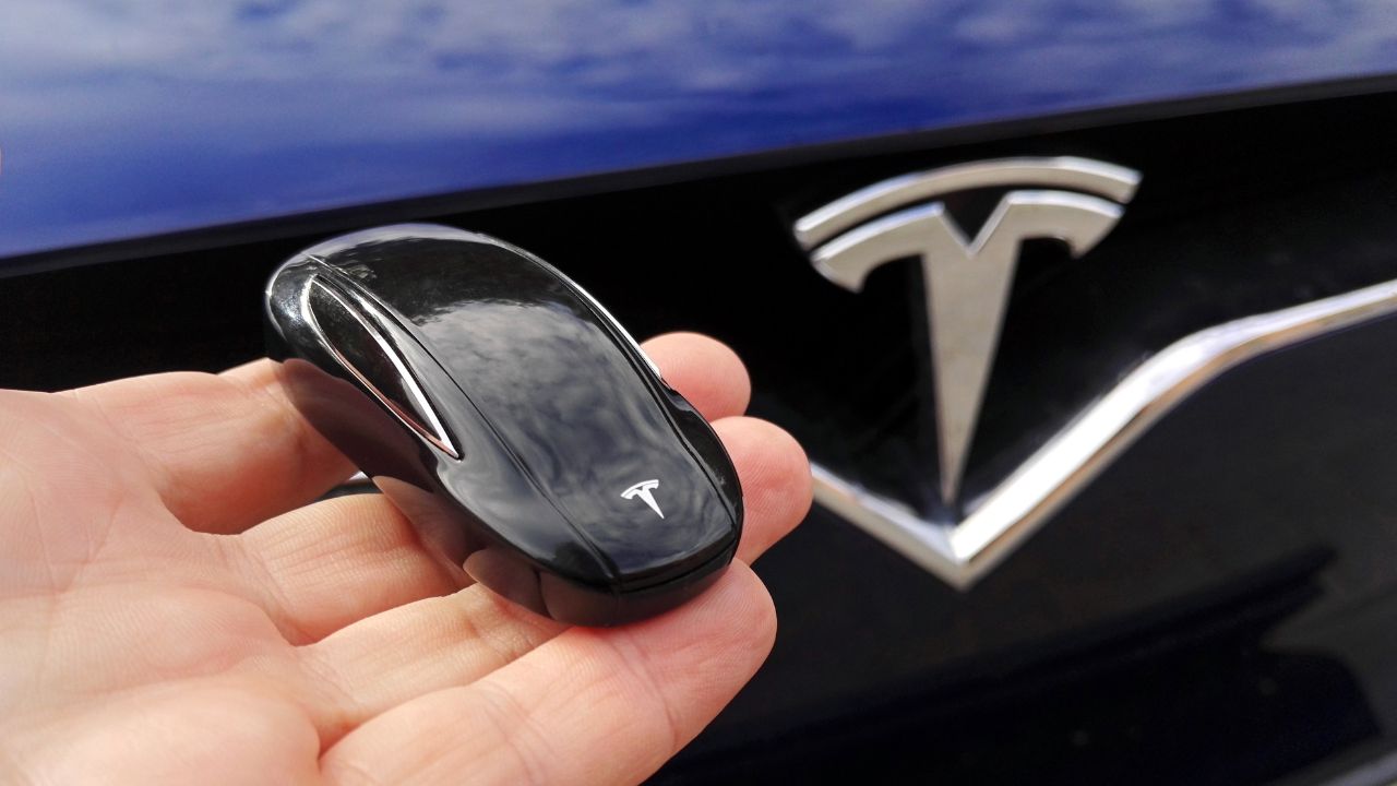 Key for Tesla car on hand with Tesla Model X car , Tesla logo