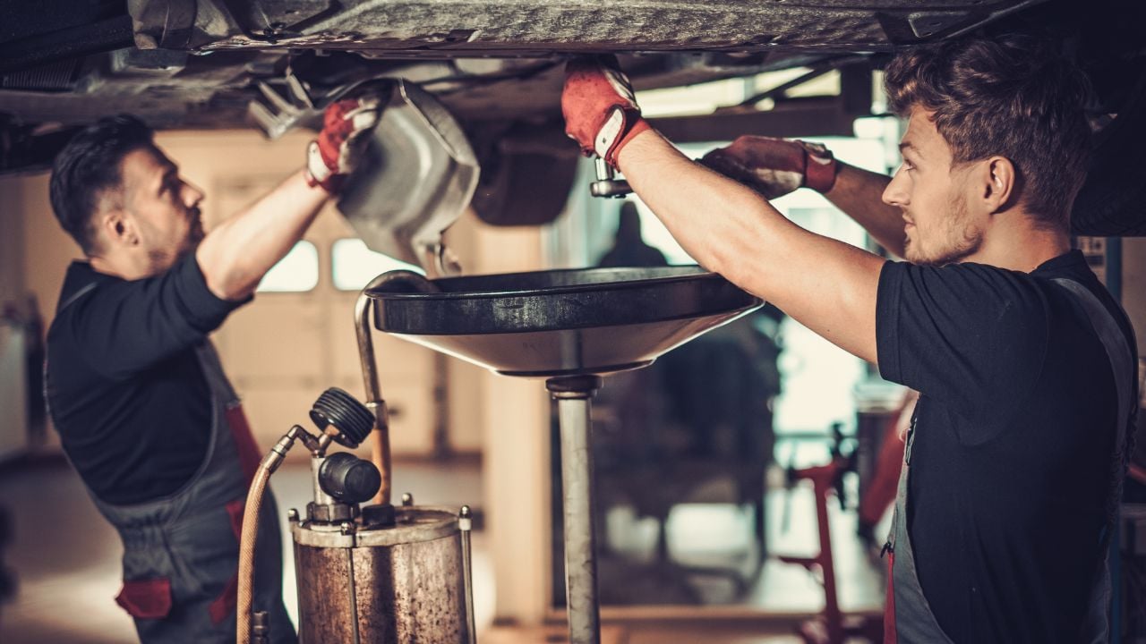 Two mechanics changing oil