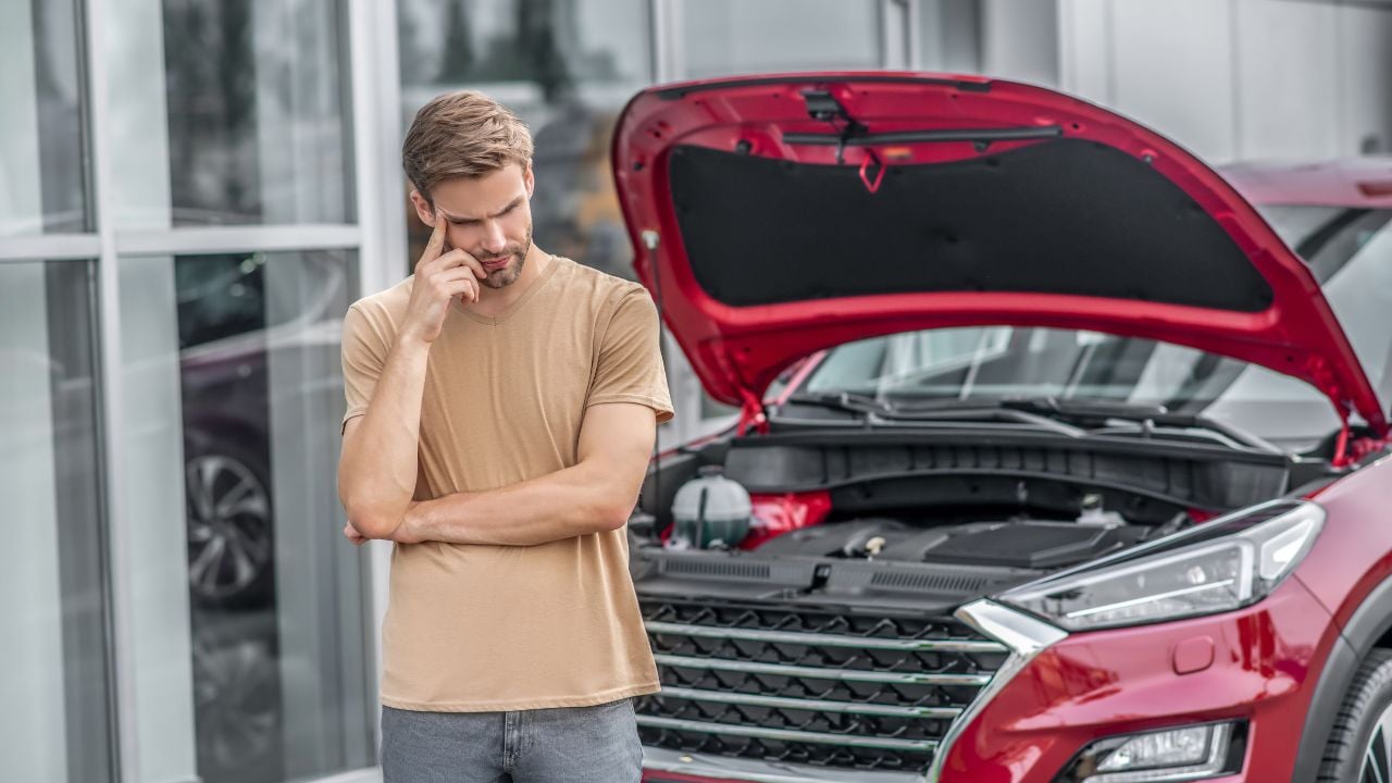 Car breakdown. Upset male driver standing in front of broken car with open hood