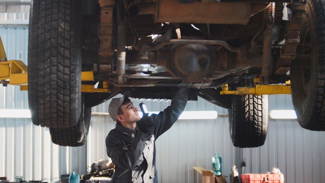 Mechanic Inspecting Off-Road SUV Suspension on Lift