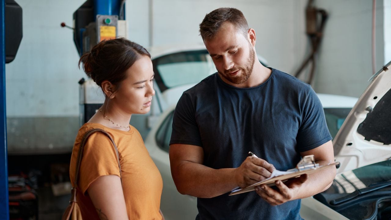 Mechanic Explaining Car Repair Paperwork to Customer in Auto Shop