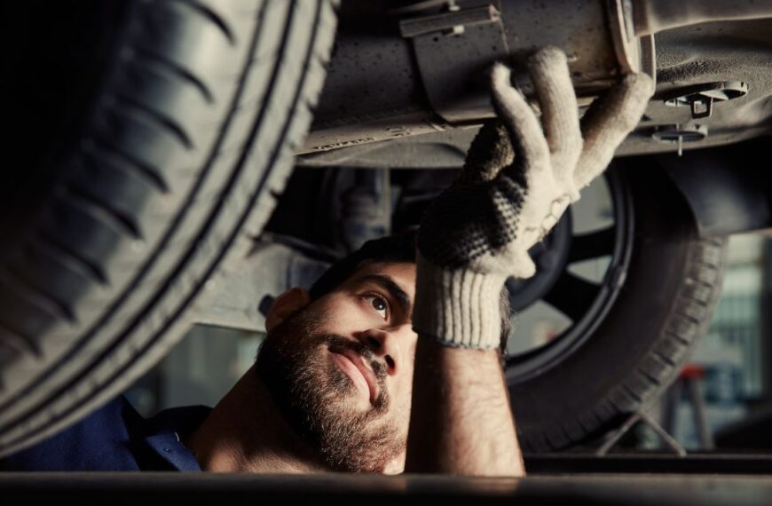 Mechatronics engineer examining the exhaust of a car in the car workshop