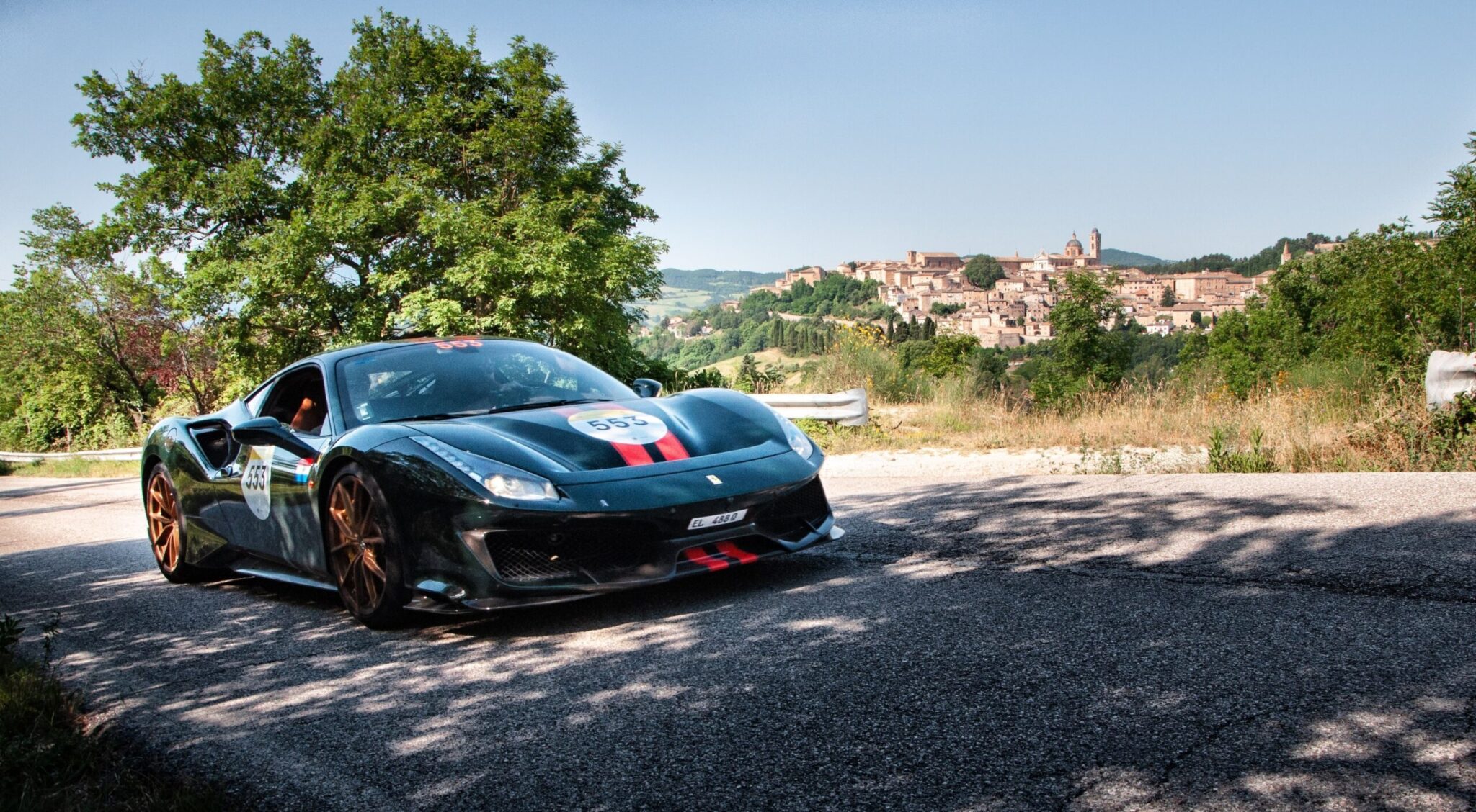URBINO, IT - Jun 06, 2022: The black Ferrari 488 Pista during the Mille Miglia 2022 with the Urbino city in the background