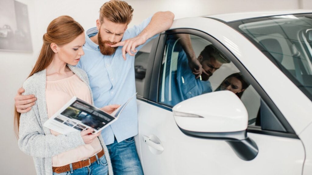 couple thinking about a car purchase at a dealership