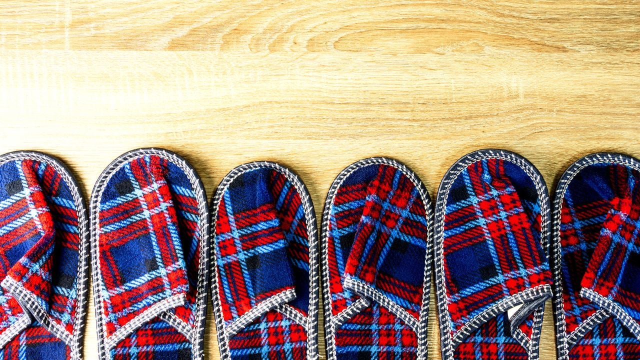A lot of colorful comfortable, cushioned, checkered disposable slippers are on the wooden floor. Top view. Concept of hospitality. Close-up. Indoors.