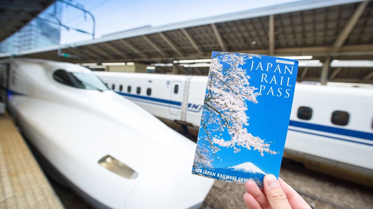 Tokyo, Japan - Dec 11, 2019: Japan Rail Pass Image, hand hold JR Pass ticket in front of Shinkansen at Tokyo Station. JR Pass is a rail pass coupon for overseas visitors unlimited bullet train ride.
