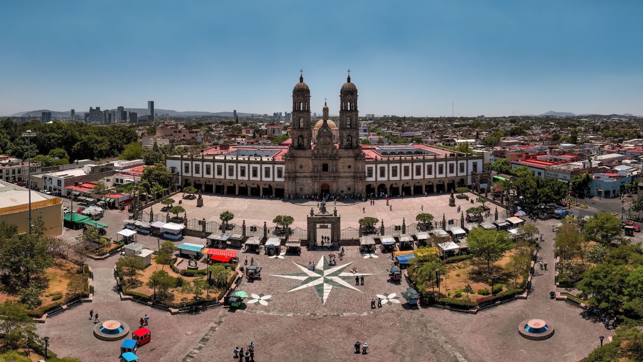 Panoramic view of the Tlaquepaque Plaza and church in Guadalajara, Mexico, under a clear blue sky, showcasing urban architecture and vibrant culture.
