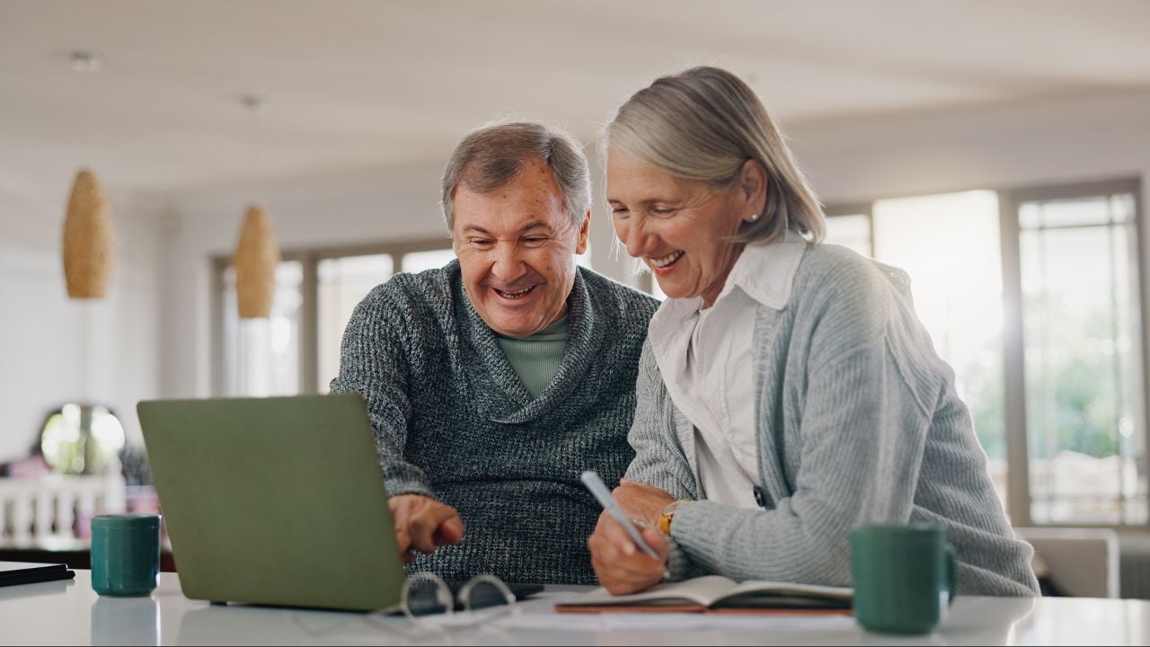 Senior man, woman and laptop with paperwork, writing and happy with profit, investment and retirement. Elderly people, couple and computer with documents for pension, review and financial freedom