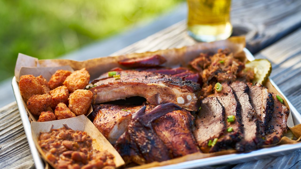 tray of smoked meats texas bbq style outside on picnic table on sunny summer day