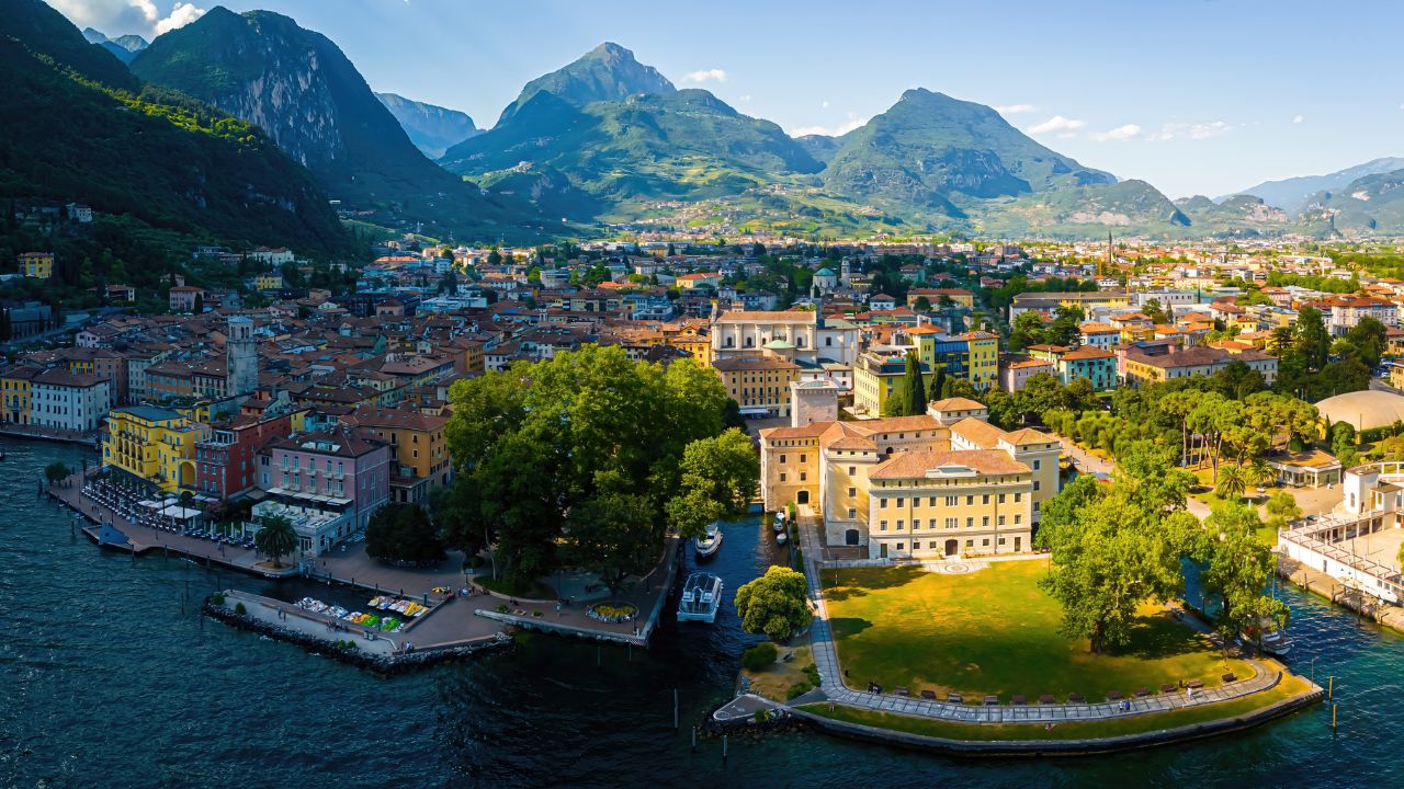 Stunning aerial capture of Riva del Garda on Lake Garda’s northern shore in Italy, with a vibrant townscape, boats, and surrounding mountains. Perfect for travel, tourism, and destination marketing.