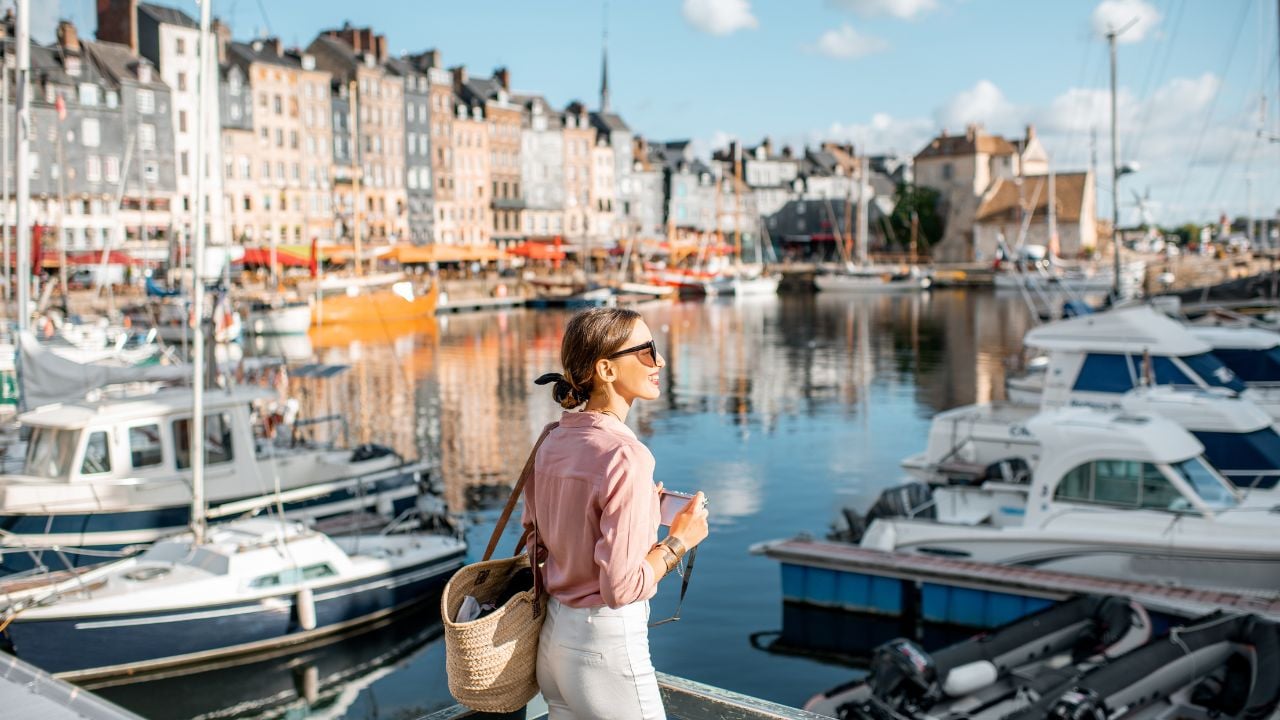 Young woman tourist enjoying beautiful view on the harbour traveling in Honfleur town in Normandy, France