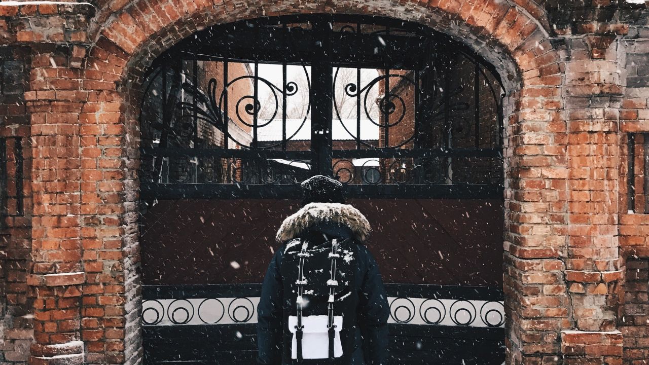 Back view of incognito girl standing in front of antique brick gate. Copyspace