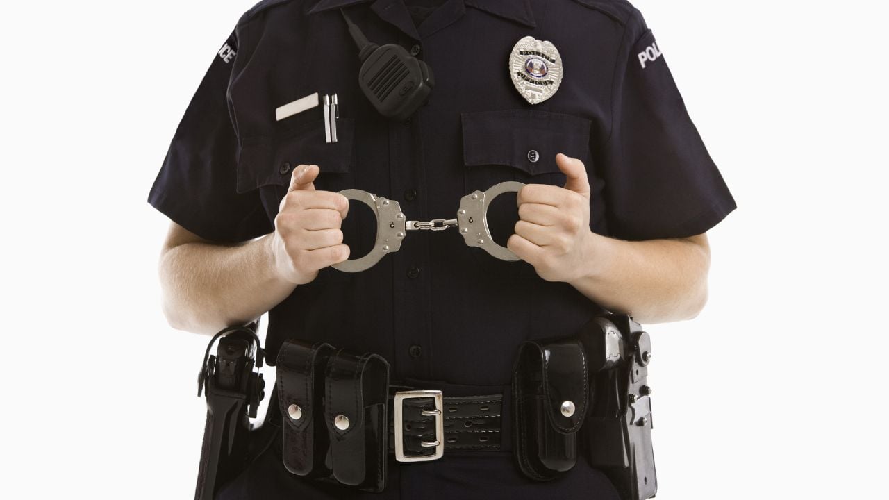 Close up of mid adult Caucasian policewoman holding locked handcuffs.