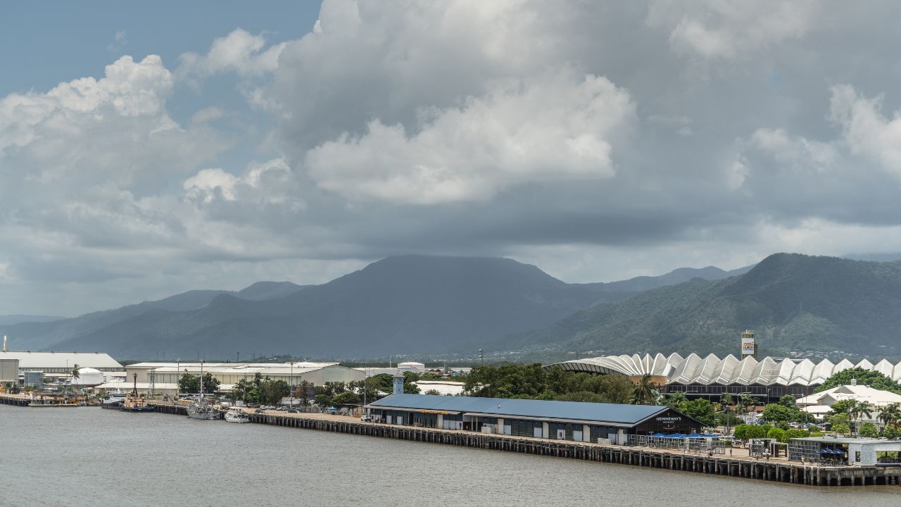 Cairns, Australia - February 17, 2019: Cruise Liner Terminal with convention center in back. Further up "Chinaman Creek," industrial warehouses. Kuranda National Park mountains under cloudscape.