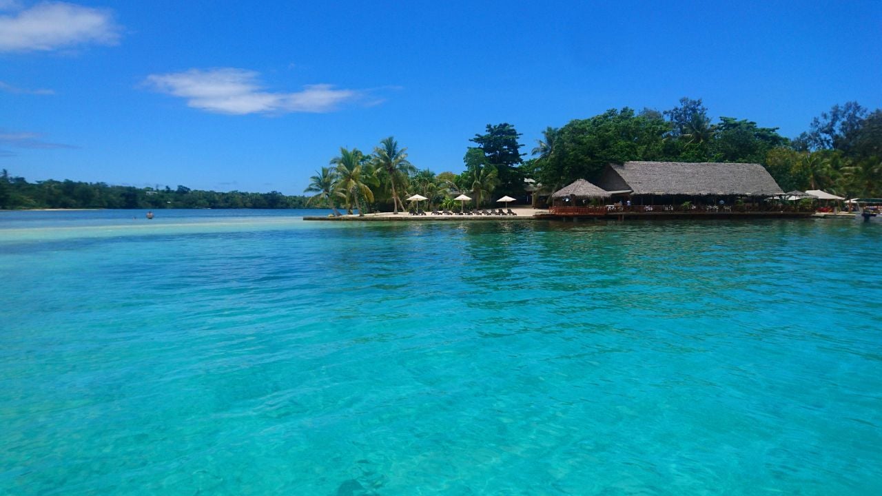 Flying near breathtaking oceanfront bar on spectacular exotic island. Empty recliner chairs are heating up on beautiful remote beach under the hot tropical sunrays in Vanuatu. Perfect holiday