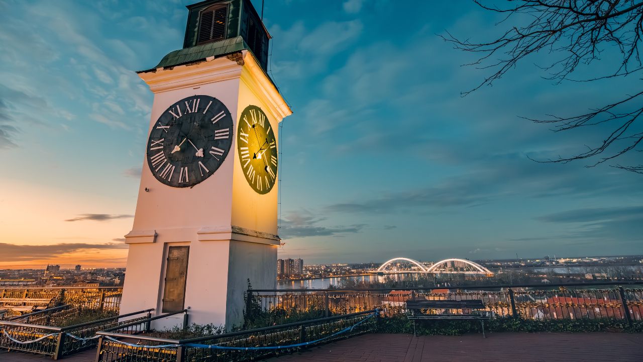 sun sets over Novi Sad, the iconic clock tower of Petrovaradin Fortress stands tall, offering a picturesque view of Serbian history and culture.