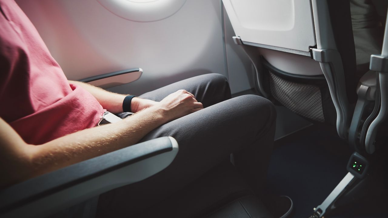 Man resting during flight. Legroom between seats in commercial airplane.