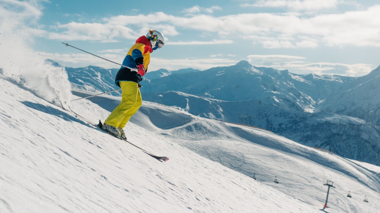 Dynamic picture of woman skier in blue outfit on the piste ski downhill fast motion in Alps. Active winter holidays, skiing downhill in overcast day. Ski rides on the track with swirls of fresh snow