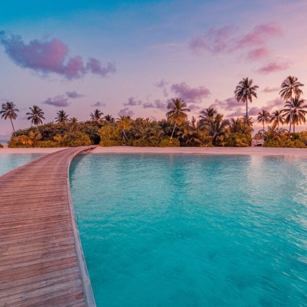 Beautiful sunset pier Maldives tropical beach with calm sea colorful sky clouds palm trees stunning majestic landscape tranquil shore paradise island nature background ideal vacation and travel scene