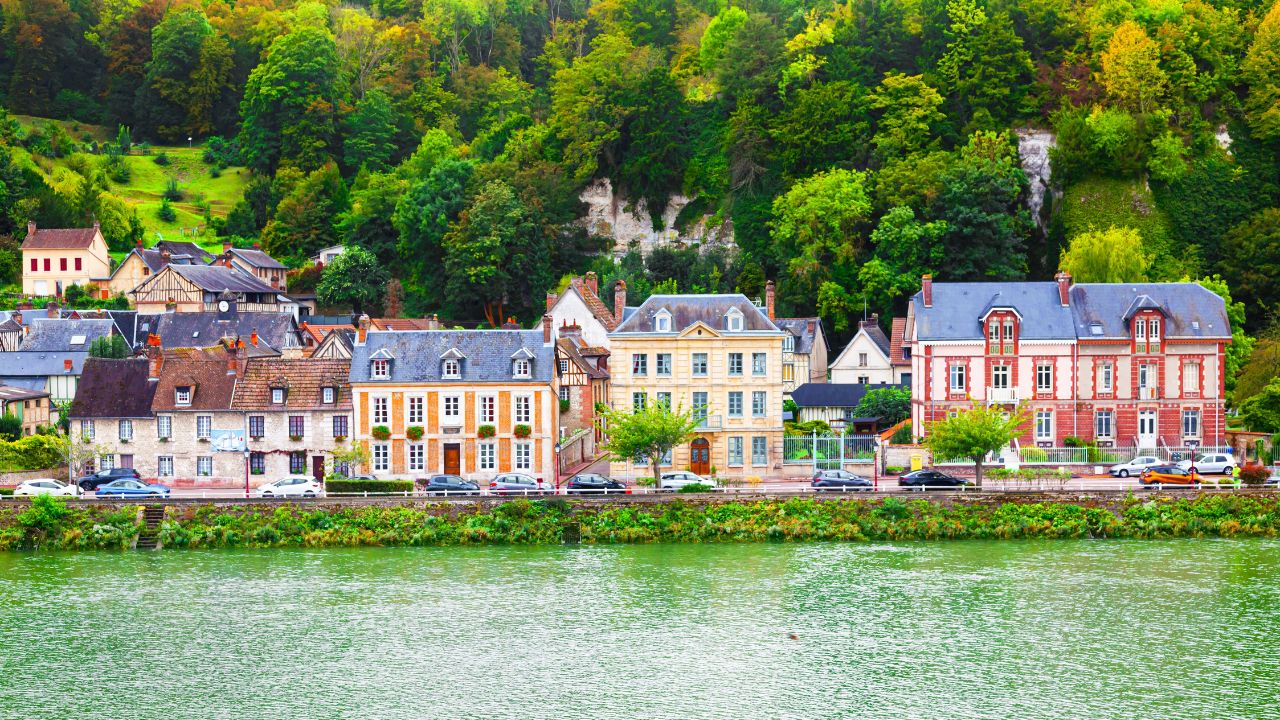 The coast of the Seine River in France in the suburbs of Rouen with beautiful private houses and dense green vegetation and mountains.