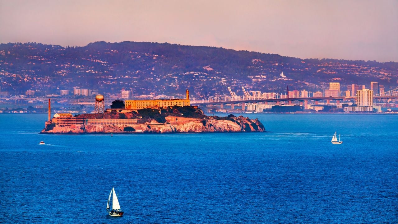 Sunset view of Alcatraz Island with sailboats in San Francisco Bay