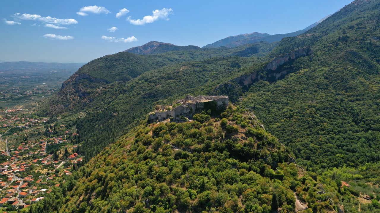 Aerial drone photo of iconic medieval byzantine uphill castle of Mystras with great scenic view to town of Mystras and Monasteries, Sparta, Peloponnese, Greece