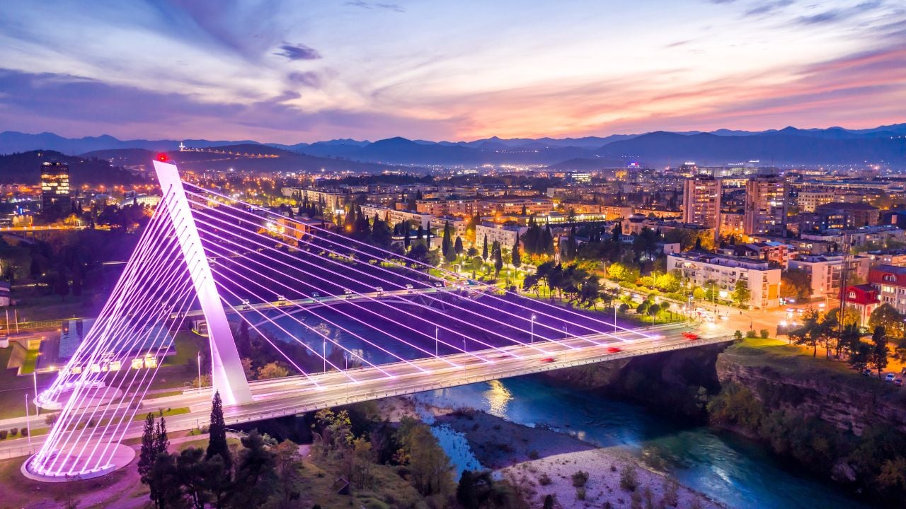 Podgorica, Montenegro, at night, featuring illuminated Millennium bridge in the city center, under colorful sunset sky. Cityscape of the capital of a small country in the Balkans, south east Europe.