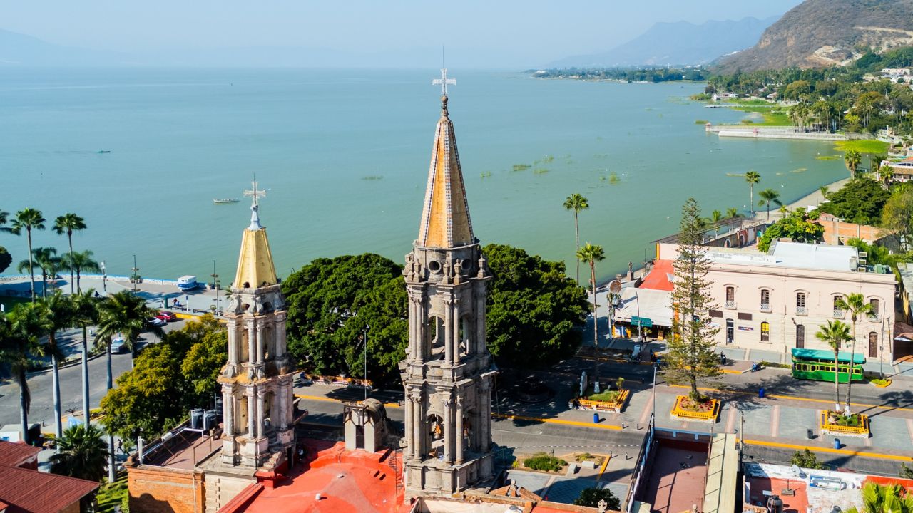 Aerial view of chapala, mexico, showcasing church towers, lake chapala, boardwalk, and town on a sunny day