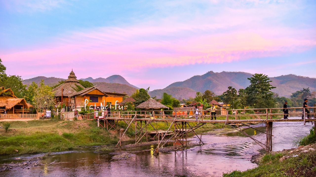 Pai / Thailand - 11 January 2016: Bridge over the Pai river, village and mountains
