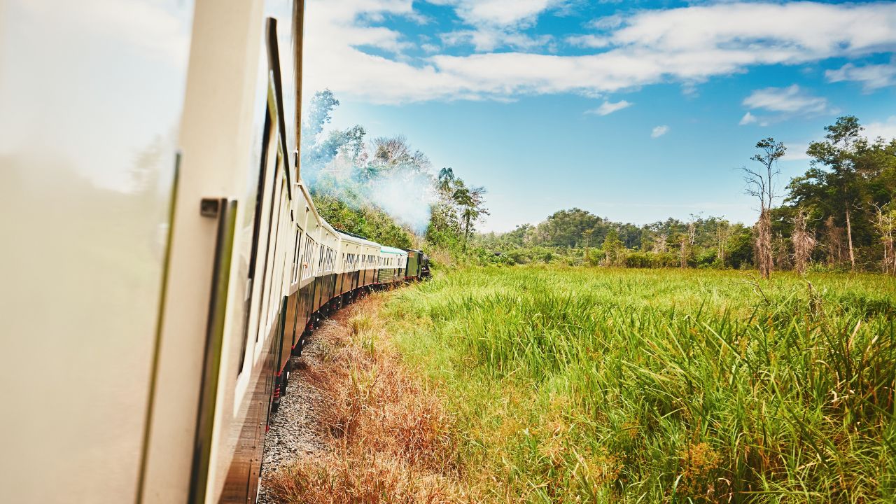 View from window of the steam train passing through countryside in Malaysia.