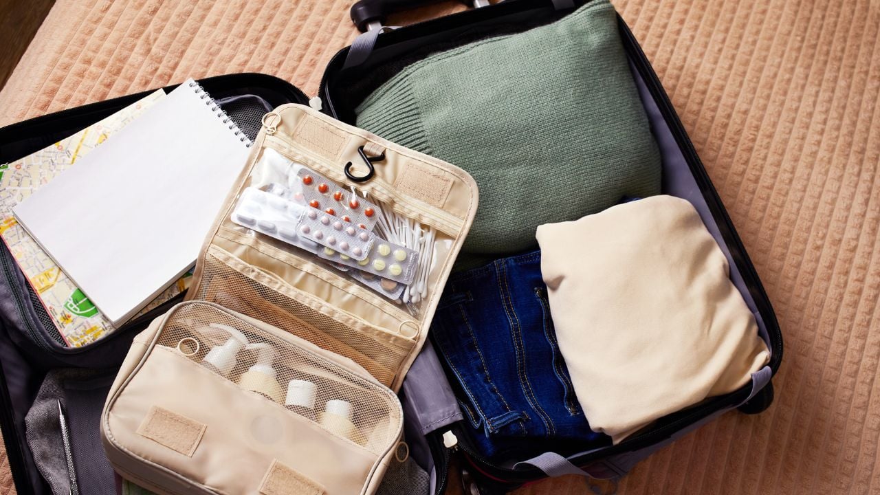 An open suitcase with a travel set of cosmetics and hygiene products, clothes, a travel guide and other necessary things for the trip.